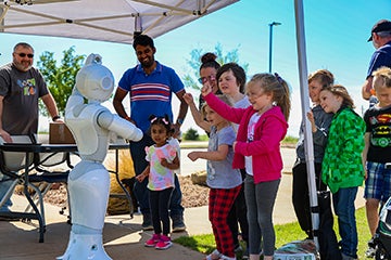 Children interacting with Pepper the robot at Co-op Kids Day. 