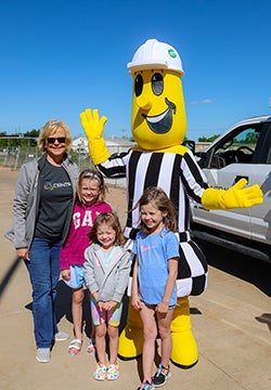 A family posing with Willie Wiredhand at Co-op Kids day. 
