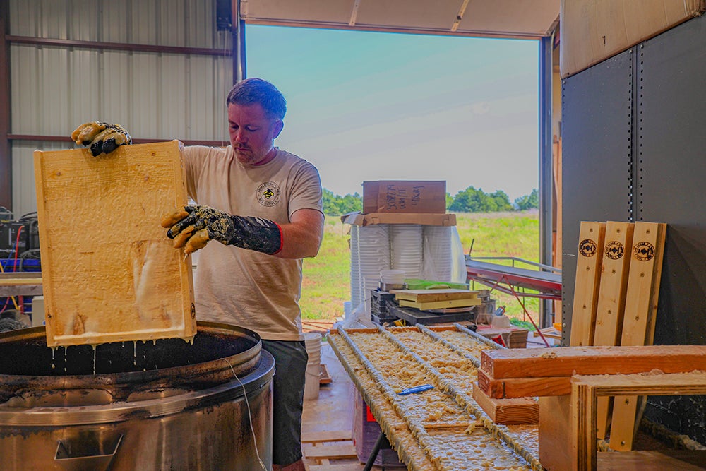 Triple Oak Bee Supply owner Dustin Cantrell dipping products in wax.